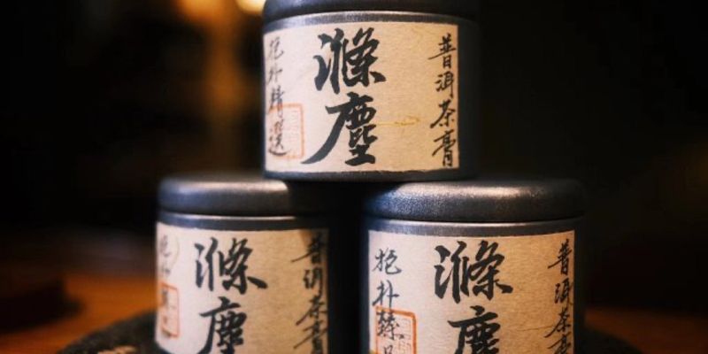 Three small dark tins labeled in Chinese, stacked in a pyramid on a dark table