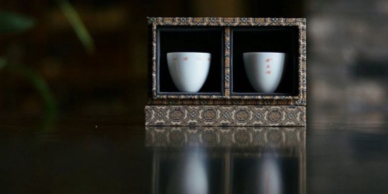 A pair of white porcelain cups set inside a brocade-lined display box